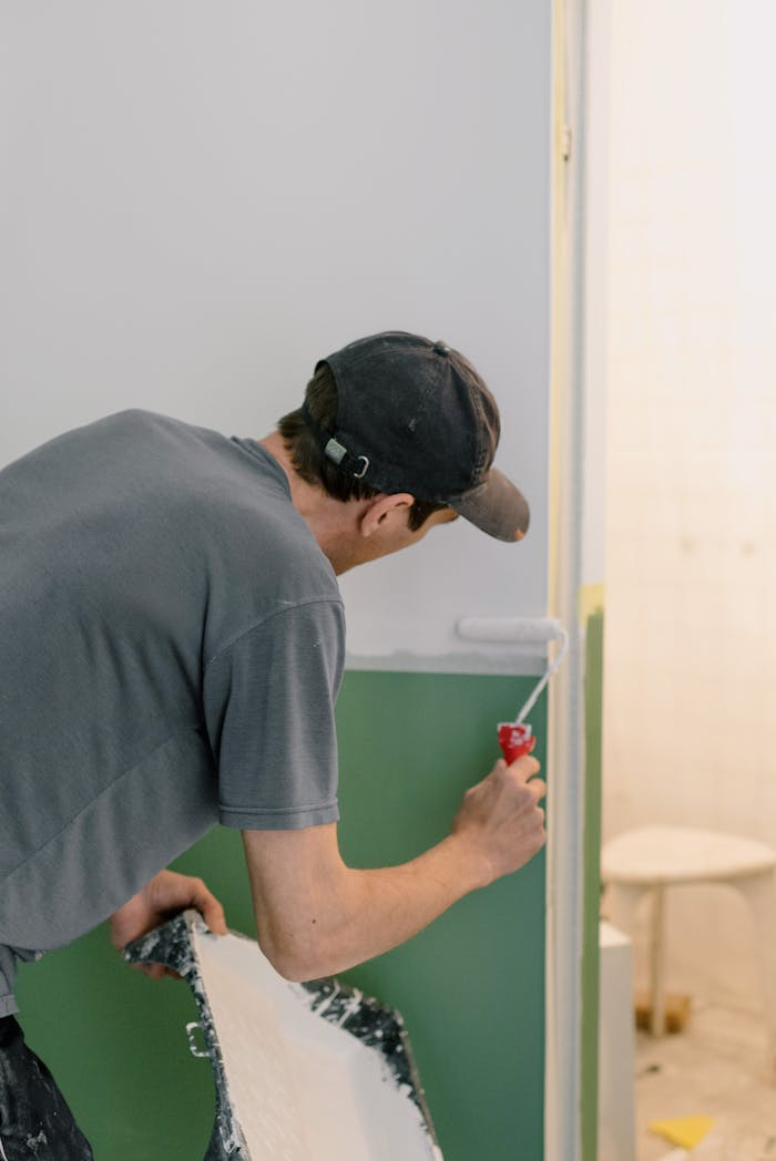 A man painting walls with a roller during home renovation indoors.